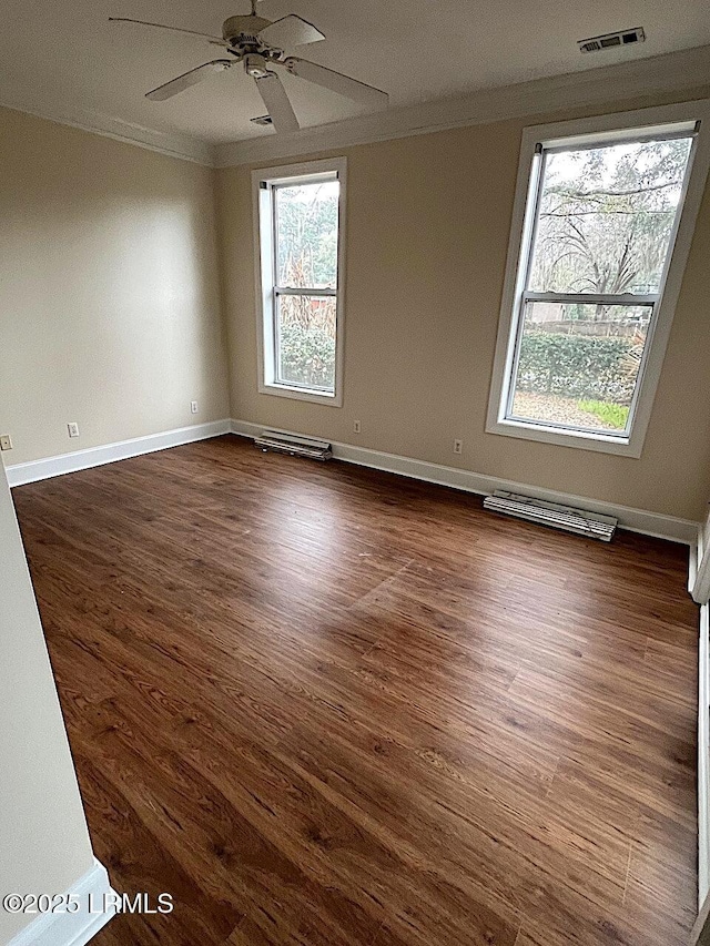 empty room featuring ornamental molding, dark wood finished floors, and visible vents