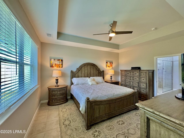 bedroom featuring light tile patterned floors, visible vents, baseboards, and a raised ceiling