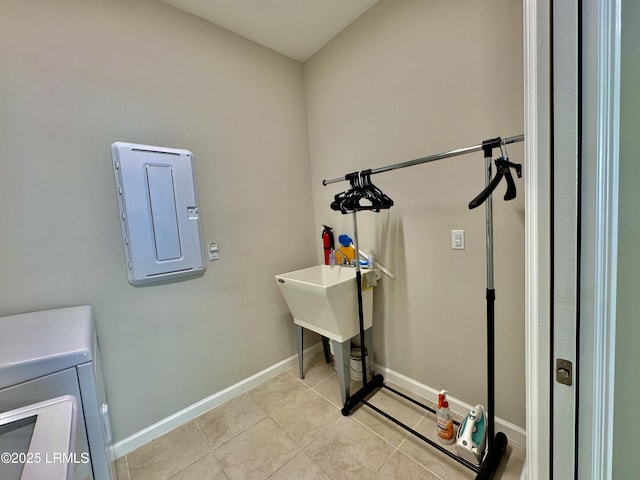 clothes washing area featuring baseboards, electric panel, laundry area, washer and clothes dryer, and light tile patterned flooring