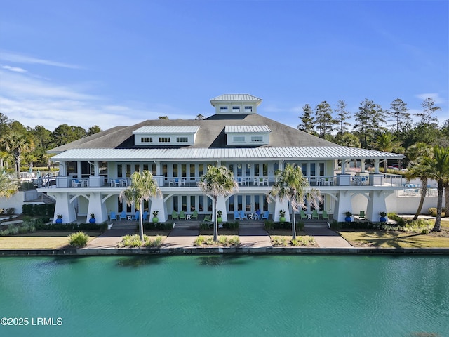 rear view of property featuring a water view, metal roof, a balcony, and french doors
