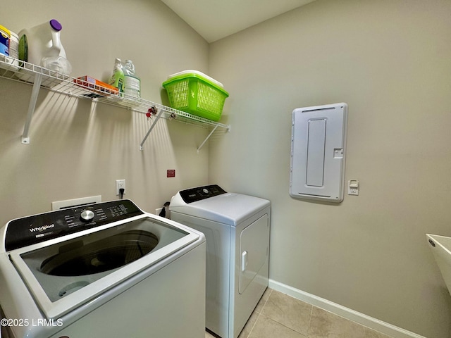 laundry room featuring light tile patterned floors, baseboards, electric panel, laundry area, and washer and clothes dryer