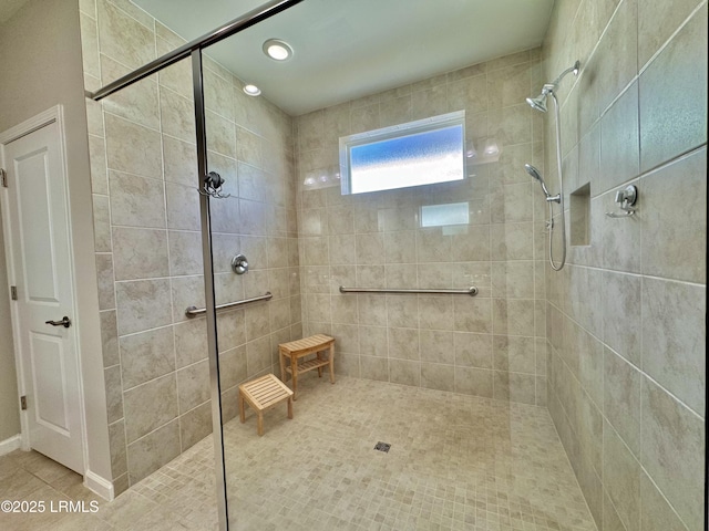 full bath featuring tiled shower and tile patterned flooring