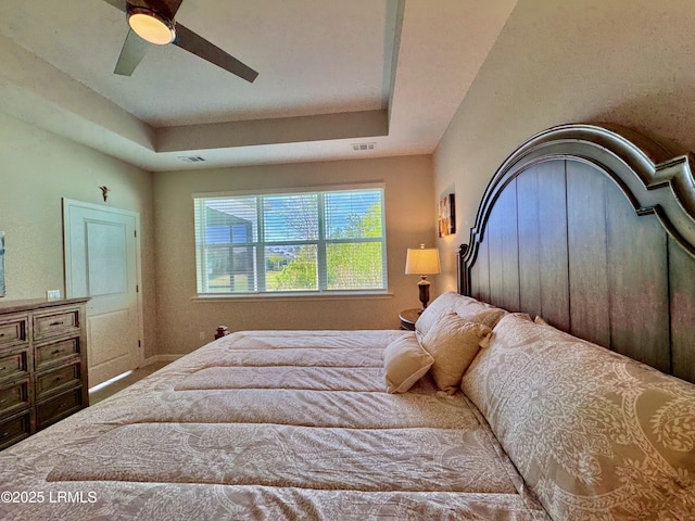 bedroom featuring a tray ceiling, a ceiling fan, and visible vents