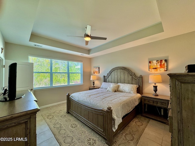 bedroom featuring visible vents, baseboards, a raised ceiling, light tile patterned floors, and ceiling fan