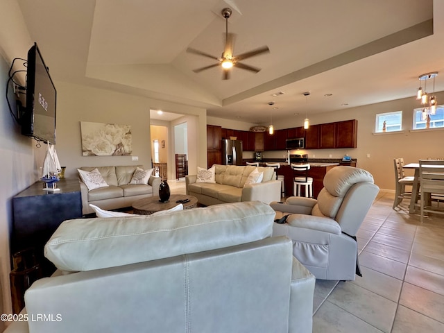 living area with lofted ceiling, a tray ceiling, light tile patterned flooring, and ceiling fan