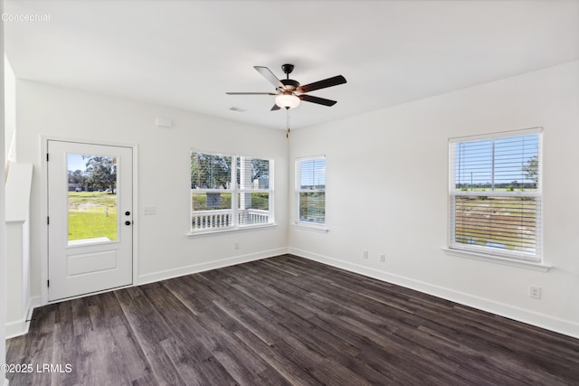 empty room with baseboards, visible vents, ceiling fan, and dark wood-type flooring