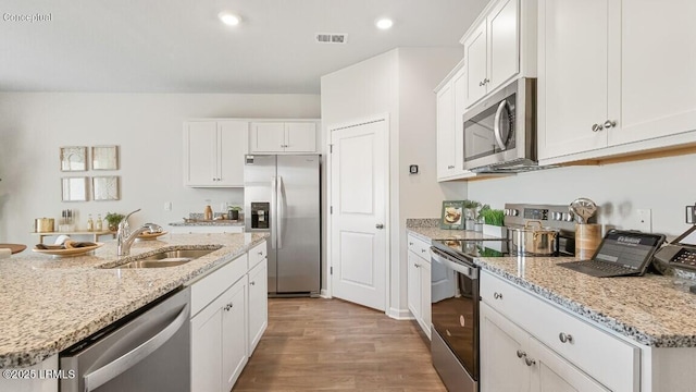 184 Twickenham Loop, Yemassee, SC 29945 - kitchen featuring stainless steel appliances, wood finished floors, white cabinetry, light stone counters, and recessed lighting