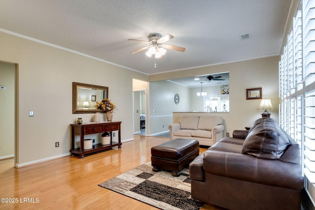 living area with visible vents, light wood-style floors, ornamental molding, and a textured ceiling