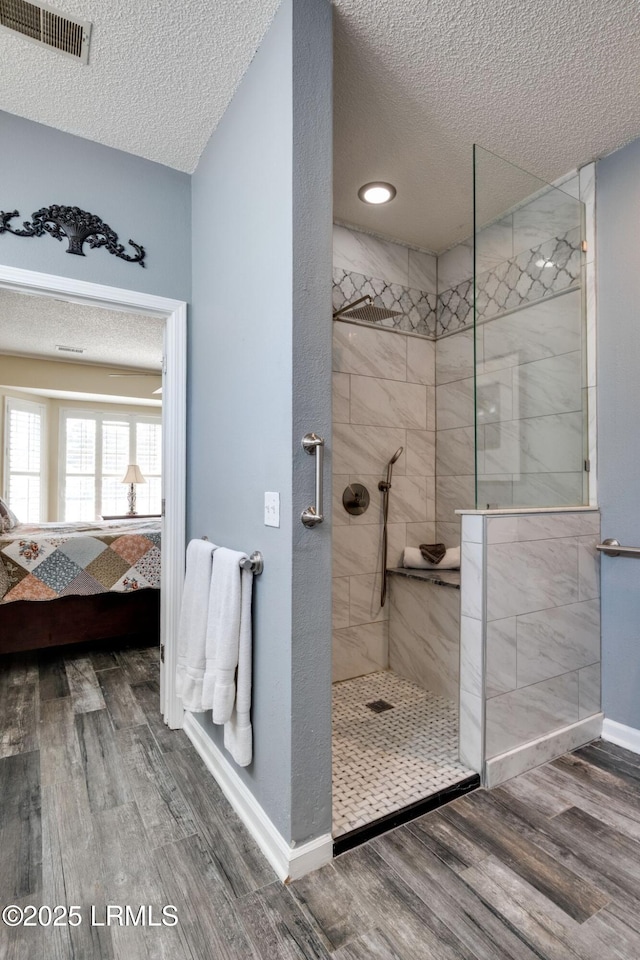 ensuite bathroom featuring wood finished floors, visible vents, ensuite bath, walk in shower, and a textured ceiling