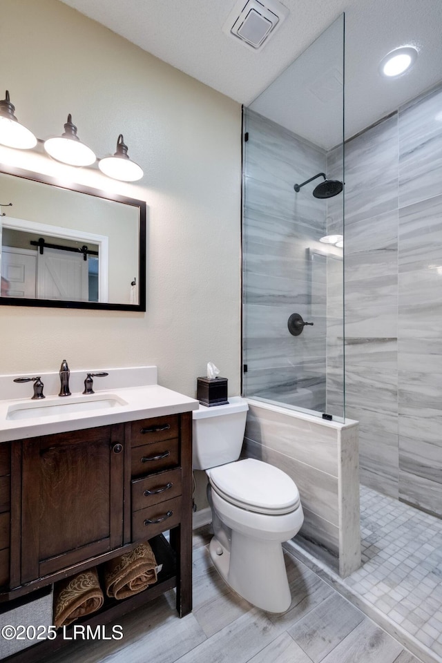 full bathroom featuring vanity, toilet, visible vents, and walk in shower