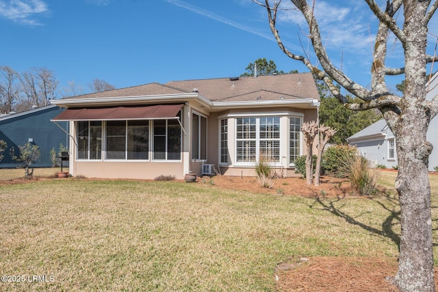 rear view of house with roof with shingles, a lawn, a sunroom, and stucco siding