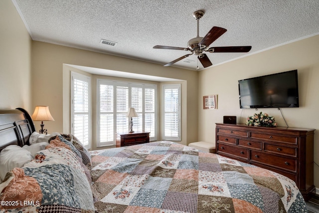 bedroom featuring visible vents, a textured ceiling, crown molding, and ceiling fan