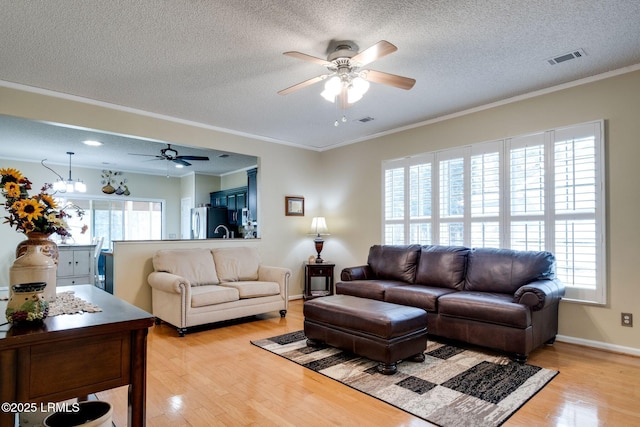 living room featuring visible vents, plenty of natural light, and light wood-type flooring