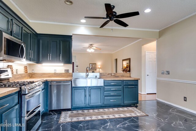 kitchen with a sink, stainless steel appliances, wood counters, crown molding, and marble finish floor