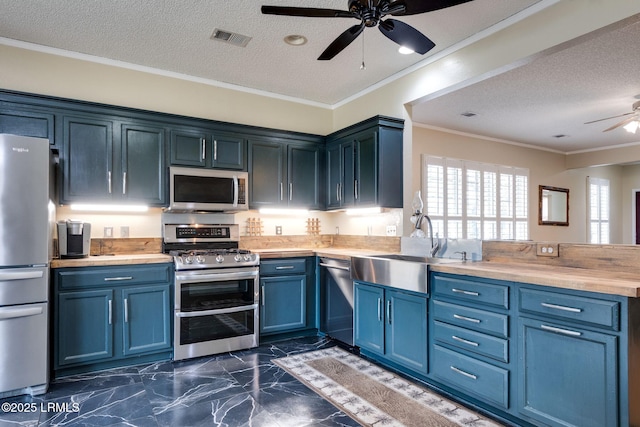 kitchen with visible vents, ornamental molding, blue cabinetry, stainless steel appliances, and a peninsula