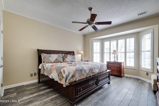 bedroom with dark wood-style floors, visible vents, a textured ceiling, and baseboards