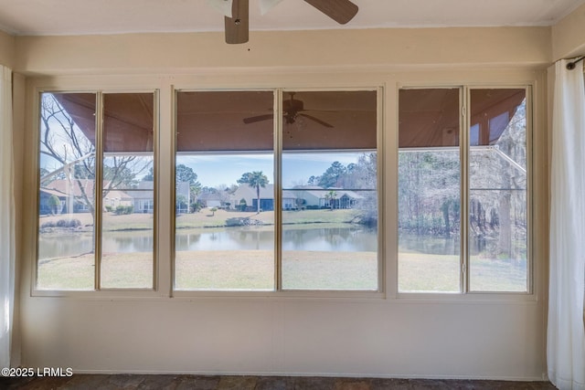 unfurnished sunroom featuring a ceiling fan and a water view