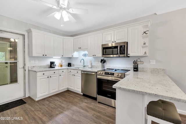 kitchen with sink, a breakfast bar area, white cabinetry, stainless steel appliances, and kitchen peninsula