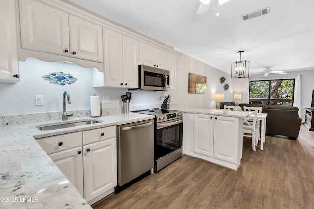 kitchen with sink, white cabinets, hanging light fixtures, kitchen peninsula, and stainless steel appliances