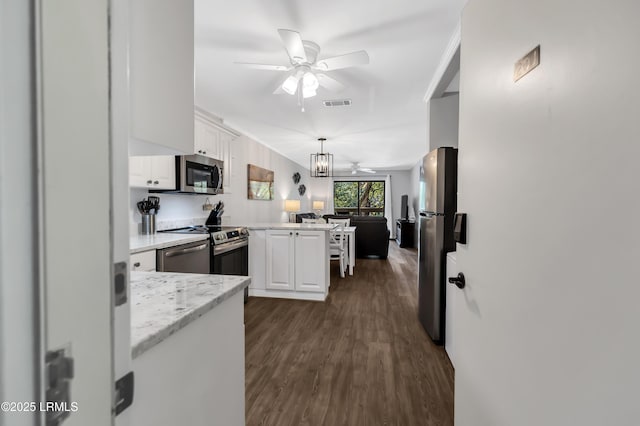 kitchen with white cabinetry, hanging light fixtures, stainless steel appliances, ceiling fan with notable chandelier, and kitchen peninsula