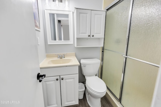 bathroom featuring vanity, toilet, a shower with shower door, and hardwood / wood-style floors