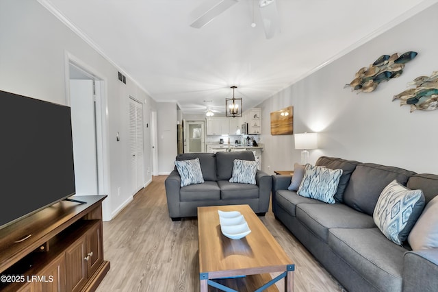 living room featuring crown molding, light hardwood / wood-style floors, and ceiling fan