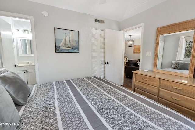 bedroom featuring lofted ceiling, connected bathroom, sink, and a closet