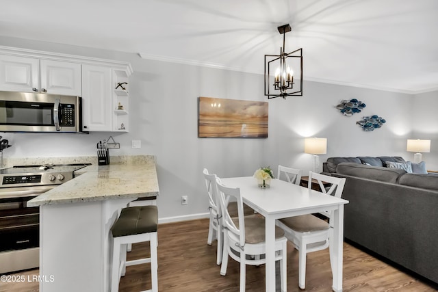 dining space with ornamental molding and light hardwood / wood-style flooring