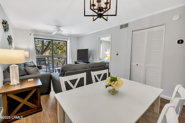 dining room with crown molding, ceiling fan with notable chandelier, and light hardwood / wood-style floors