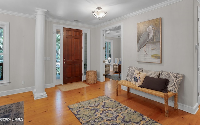 foyer featuring crown molding, decorative columns, and hardwood / wood-style flooring