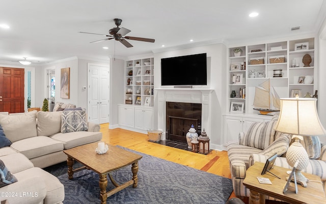 living room featuring crown molding, ceiling fan, built in features, and light wood-type flooring