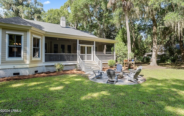 rear view of house featuring a patio, a sunroom, a yard, and an outdoor fire pit