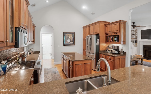 kitchen with sink, a center island, dark stone countertops, ceiling fan, and stainless steel appliances