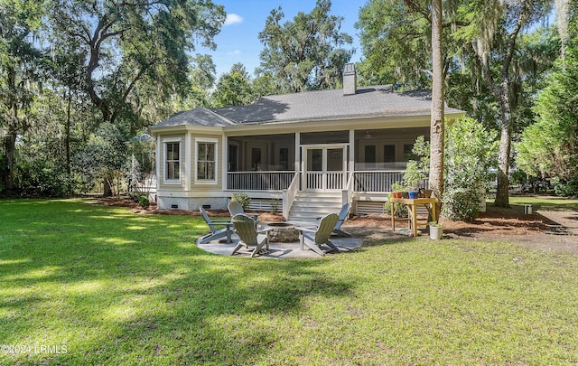 rear view of house featuring a fire pit, a lawn, and a sunroom