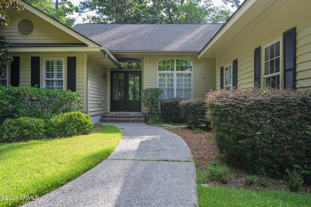 view of exterior entry featuring a lawn and french doors