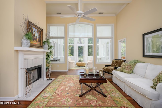 living room featuring a tile fireplace, ornamental molding, hardwood / wood-style floors, and ceiling fan