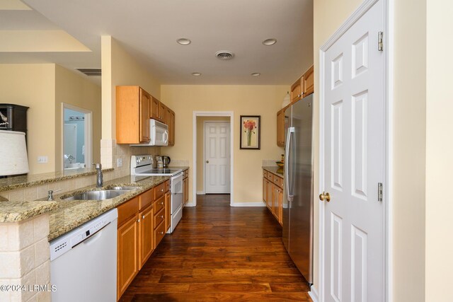 kitchen featuring dark wood-type flooring, sink, white appliances, light stone countertops, and backsplash