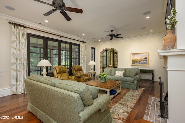 living room featuring dark wood-type flooring, ceiling fan, and crown molding