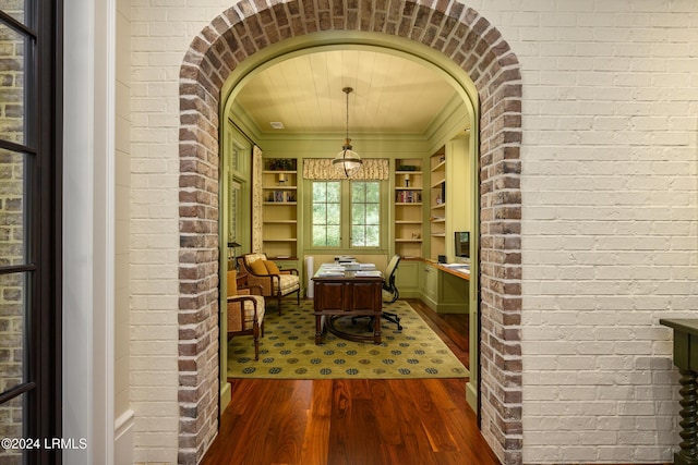 interior space with dark wood-type flooring and brick wall