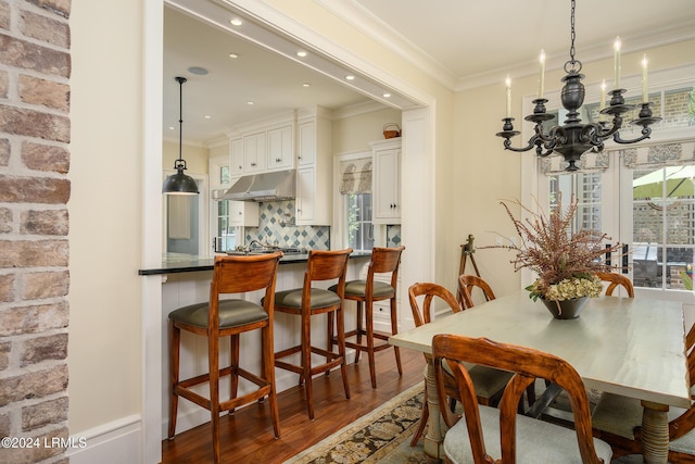 dining area with ornamental molding, a notable chandelier, and dark hardwood / wood-style flooring