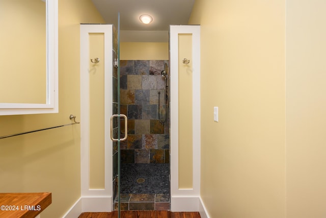 bathroom featuring wood-type flooring and a shower with shower door