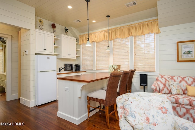 kitchen featuring pendant lighting, wood counters, wooden walls, dark hardwood / wood-style flooring, and white fridge