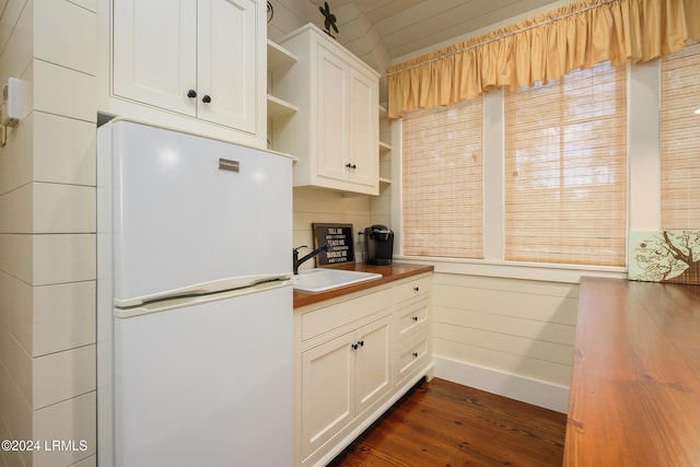 kitchen featuring dark hardwood / wood-style floors, wood counters, sink, white cabinets, and white refrigerator