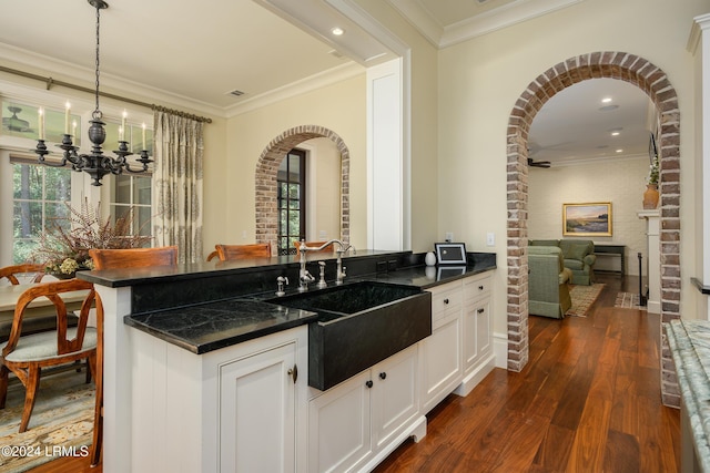 kitchen featuring pendant lighting, sink, white cabinets, and brick wall