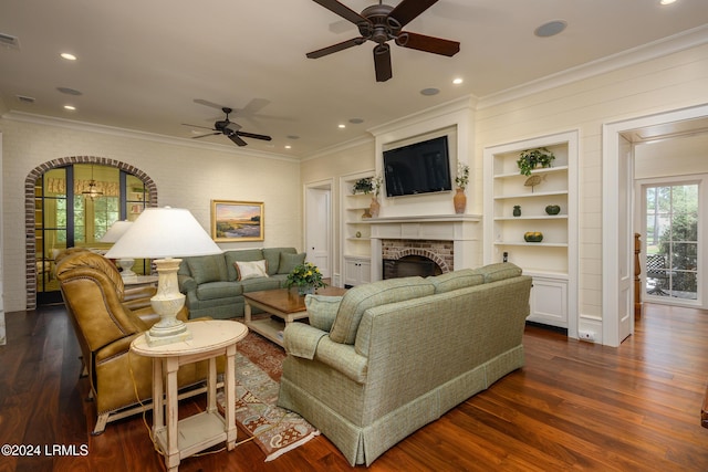 living room featuring ceiling fan, built in features, dark hardwood / wood-style floors, and a brick fireplace