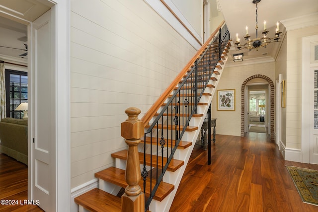 stairway with hardwood / wood-style floors, a notable chandelier, and ornamental molding