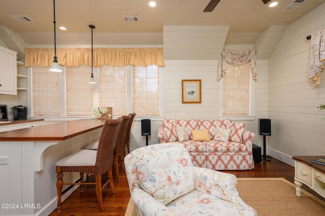 living room with ceiling fan, wooden walls, and dark hardwood / wood-style flooring