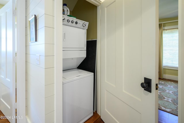 washroom featuring dark hardwood / wood-style flooring and stacked washing maching and dryer