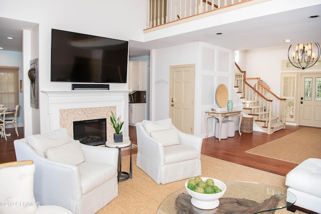 living room featuring an inviting chandelier, hardwood / wood-style flooring, a fireplace, and a towering ceiling