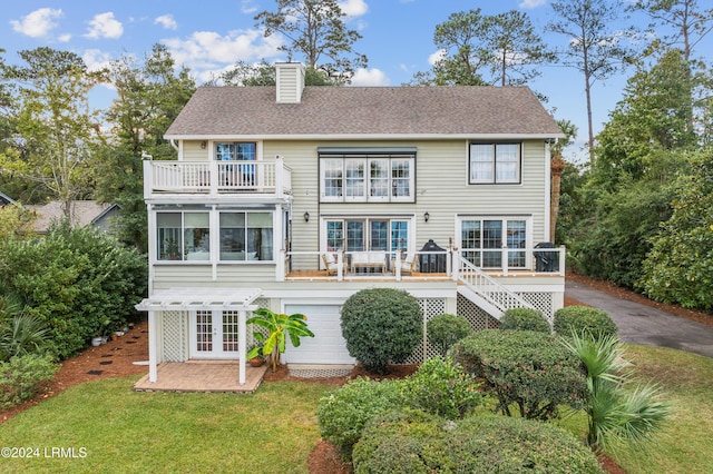 back of property with a garage, a balcony, a yard, and french doors